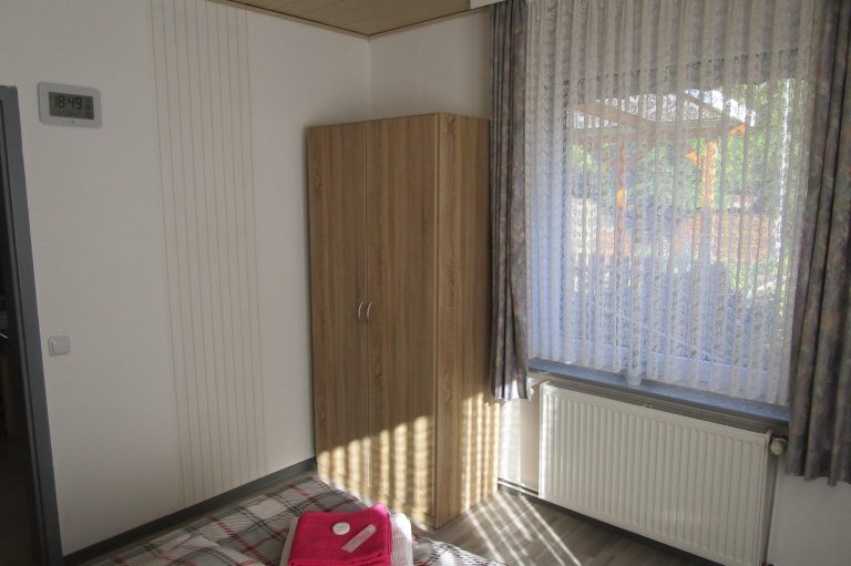 Schlafzimmer mit Kleiderschrank und Blick in den Garten Ferienhaus LEER Ferienwohnung Unterkunft Fewo